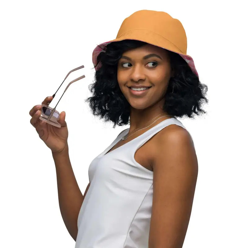 Smiling woman with curly hair rocks an orange reversible bucket hat with pink geometric print