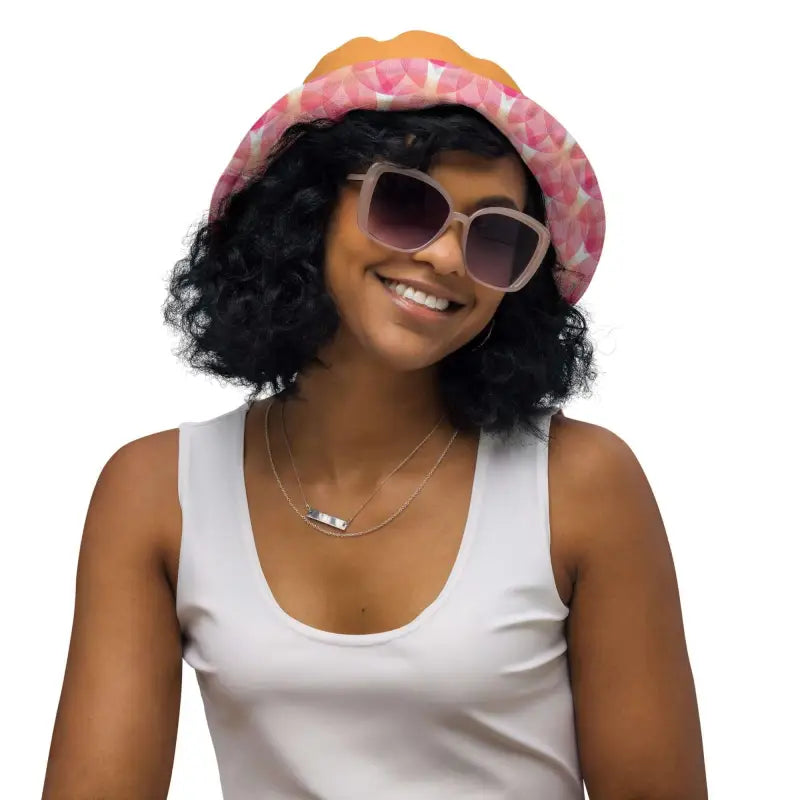 Smiling person in a colorful bucket hat showing off the Pink Geometric Print Reversible Bucket Hat