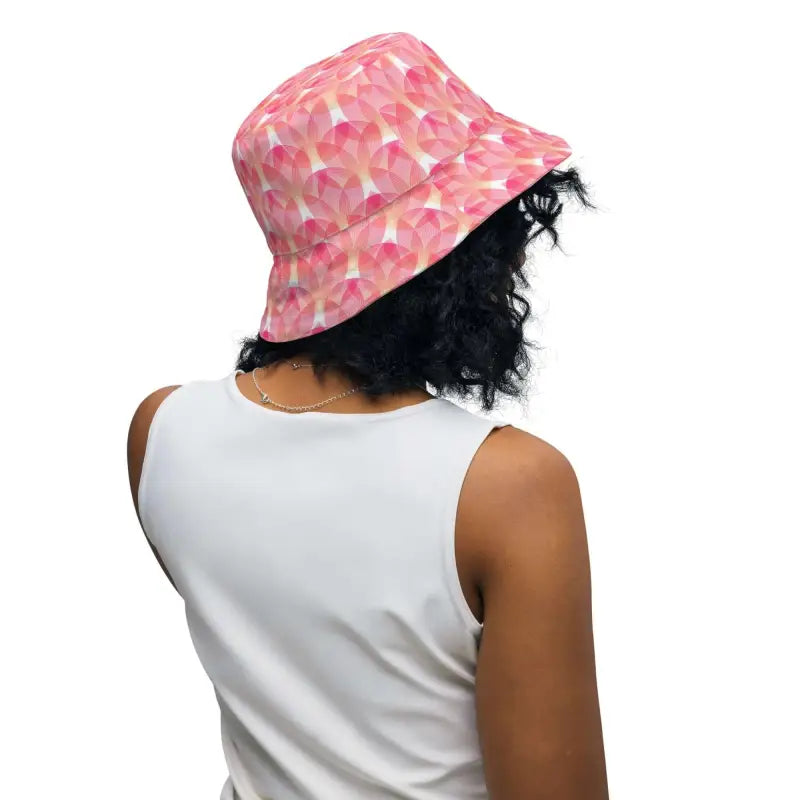 Person with dark curly hair rocking a pink geometric print reversible bucket hat