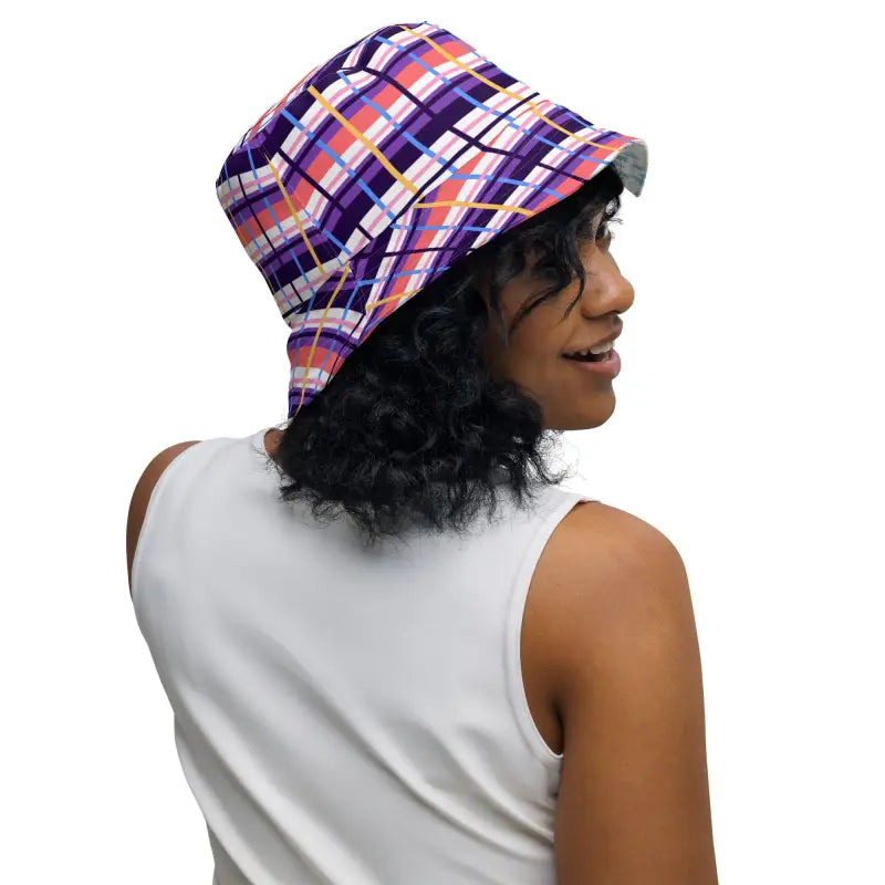 Colorful plaid bucket hat worn by a person with curly dark hair in a floral reversible bucket