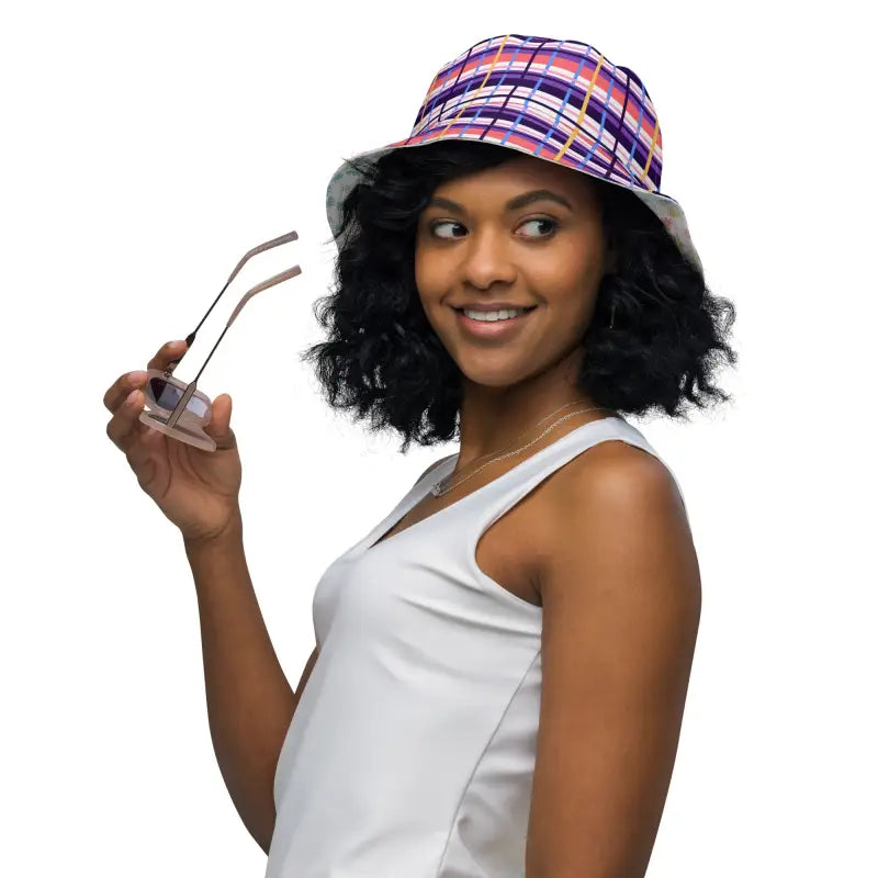 Woman rocking a colorful plaid reversible bucket hat while holding trendy sunglasses