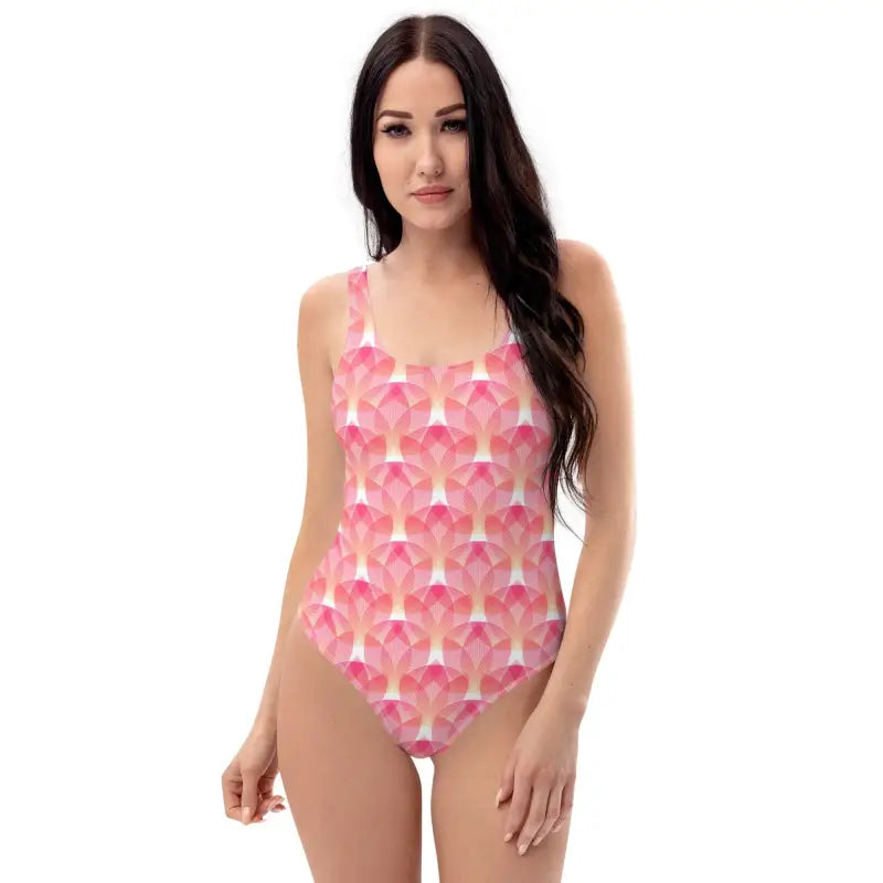 Woman with long dark hair in a pink geometric print one-piece swimsuit at the beach