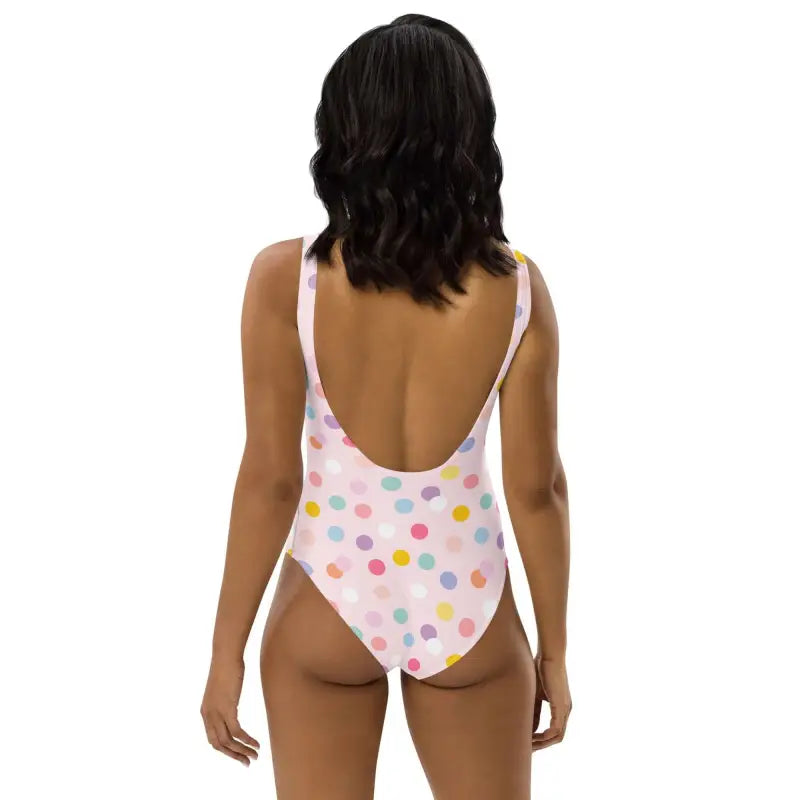 Colorful pink polka dot one-piece swimsuit with a stylish low-cut back on white background