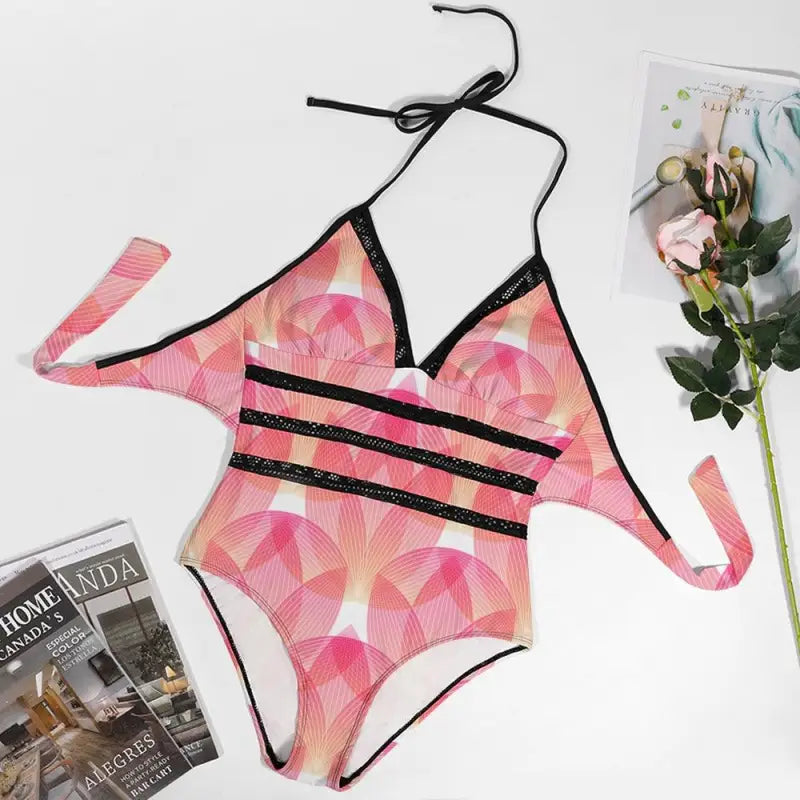 Pink geometric print one-piece swimsuit with black straps, perfect for summer fun