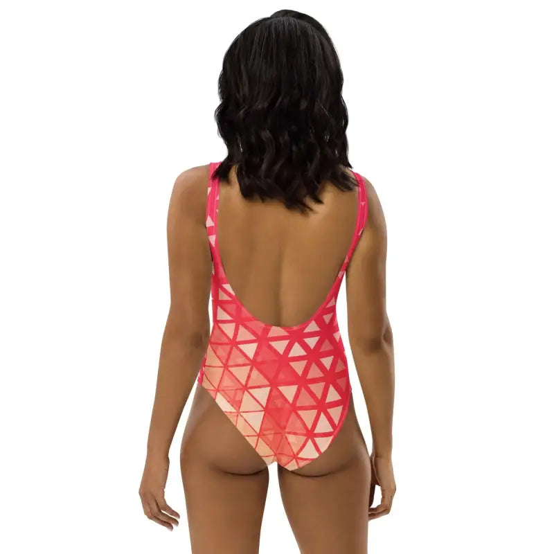 Person with dark hair in a red and white geometric print one-piece swimsuit