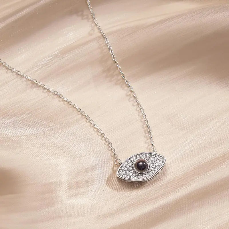 Silver evil eye projection necklace with dark gemstone and small crystals for custom style