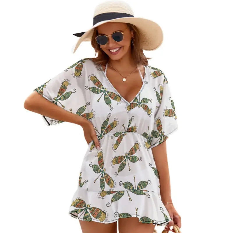White romper with green dragonfly print, beach dress style, wide-brimmed hat, and shades