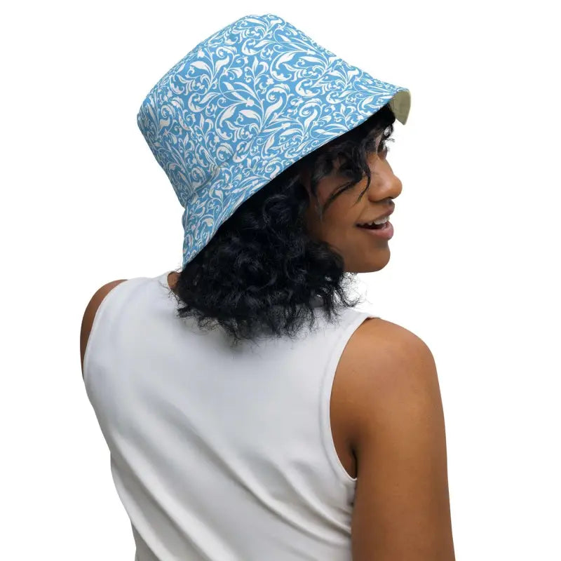 Person with curly dark hair rocking a blue floral reversible bucket hat