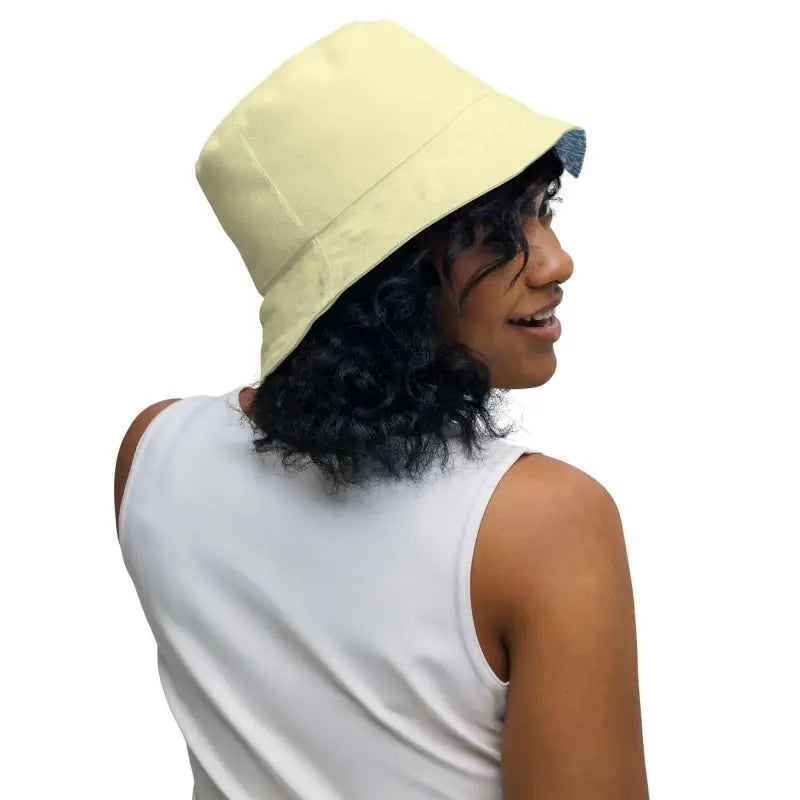 Cream-colored reversible bucket hat with blue floral design on a curly-haired model