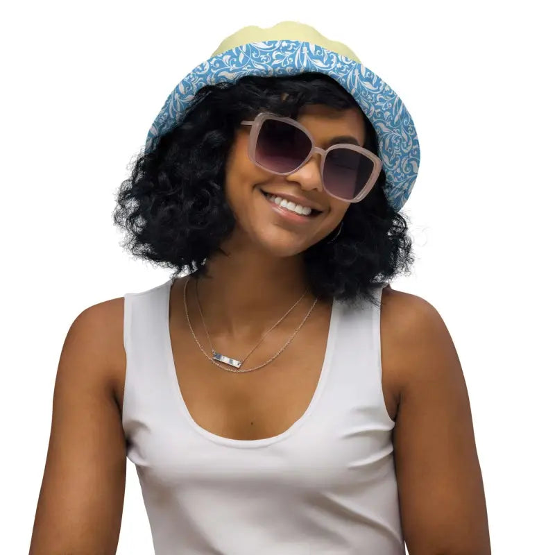 Smiling person in a blue floral reversible bucket hat and white tank top enjoying sunny vibes