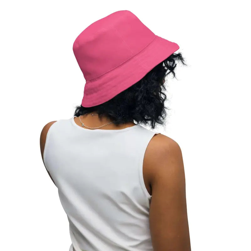 Person with curly dark hair rocking a pink polka dot reversible bucket hat