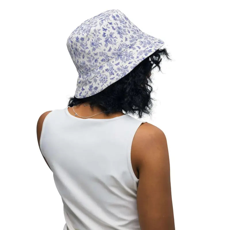Person with dark curly hair rocks a blue floral print reversible bucket hat