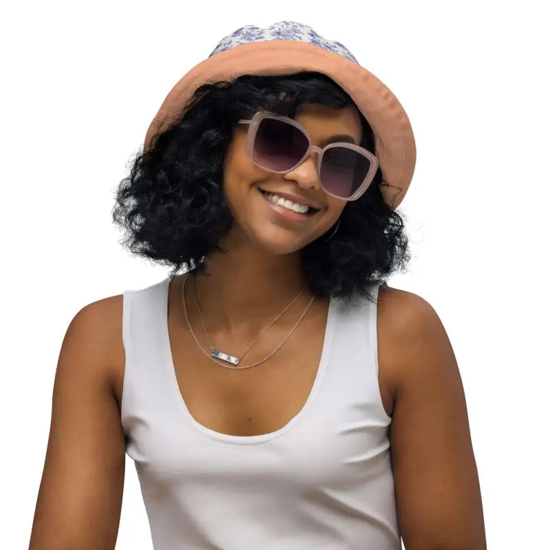 Smiling person in solid peach reversible bucket hat with sunglasses and tank top