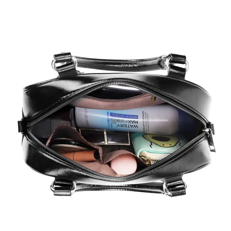 Black leather shoulder handbag unzipped, showcasing interior for sunny lunch dates