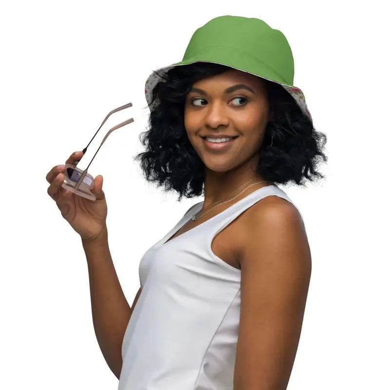 Smiling woman in a green floral print reversible bucket hat holding sunglasses