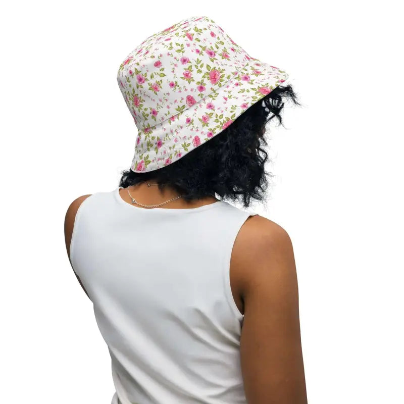Person with curly dark hair rocking a floral print reversible bucket hat in rose floral print