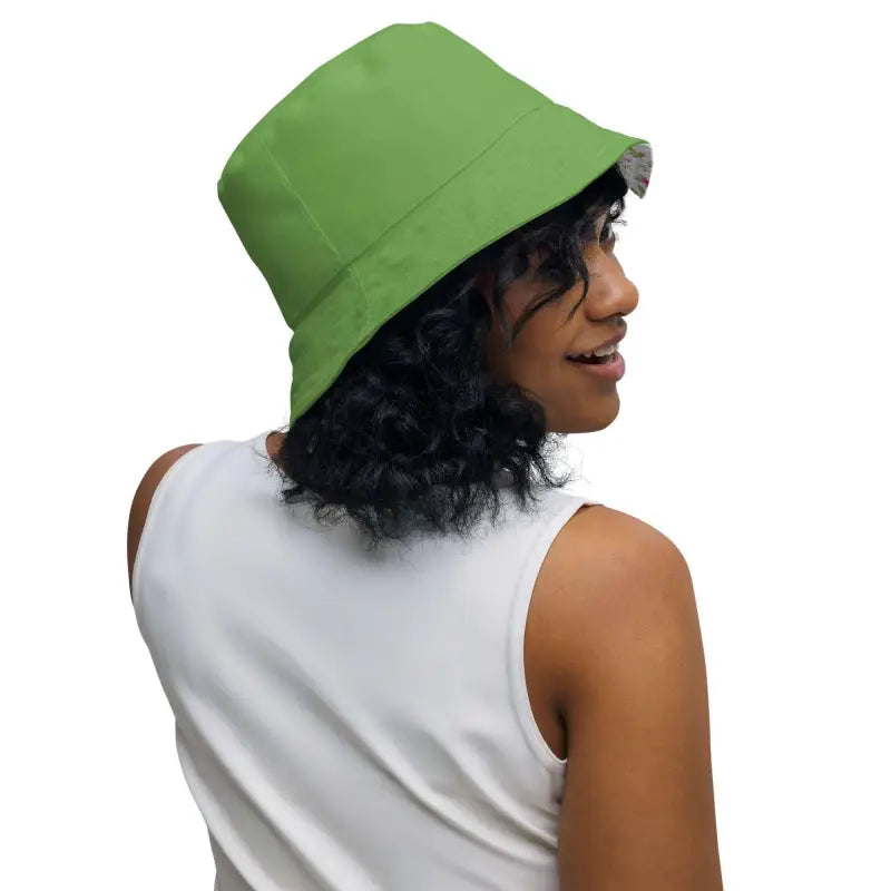 Bright green reversible bucket hat with rose floral print worn by a person with curly hair