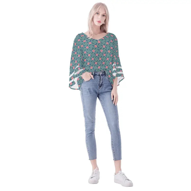 Woman in a teal floral chiffon blouse with bell sleeves and light blue jeans