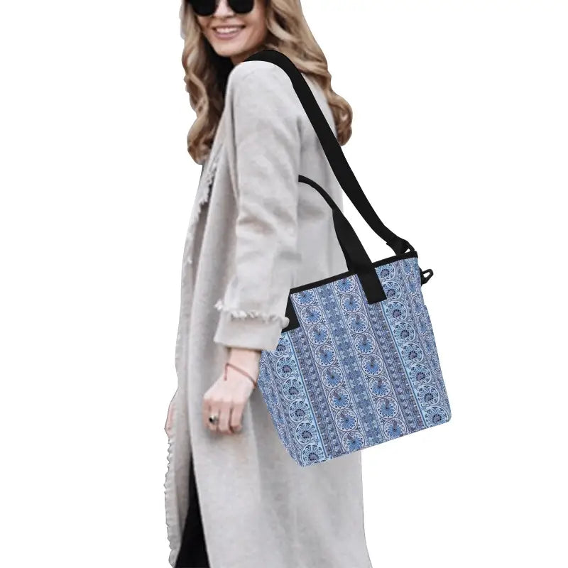 Woman in a light coat carries a blue print insulated tote bag with black straps