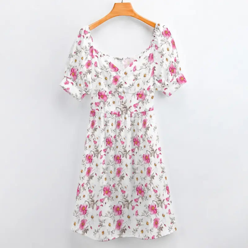 White floral sweetheart dress with pink roses and puff sleeves on a wooden hanger