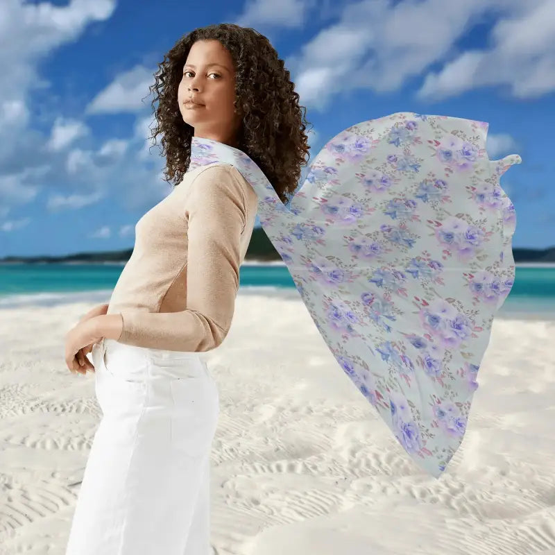 Woman in beige top and white pants on beach with flowing womens blue pattern sarong